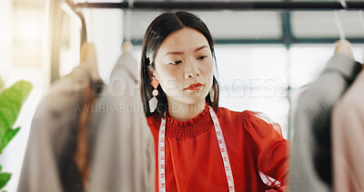 Fashion designer, woman and clothes choice on rack in shop for choosing outfit. Boutique, store and smile of happy Asian tailor or seamstress checking selection of clothing for inventory in wardrobe.