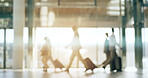 Global, airport and business people walking with luggage in a terminal for an international trip. Corporate, travel and flight with a group of professional people getting ready for departure