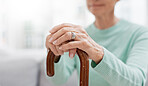 Hands, walking stick and elderly woman with walking stick on a sofa for balance, support and mobility. Walk, aid and old female at senior care facility with disability, dementia or chronic arthritis