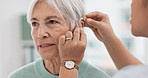 Old woman, doctor hands and patient with hearing aid, help and support with healthcare in clinic. Person with disability, deaf and people, trust and communication, health insurance and medical