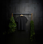 Black t-shirt mockup with copyspace on dark background with plants on hanger, front view