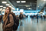 Traveling woman with backpack at international airport or large train station, departure or arrival bokeh