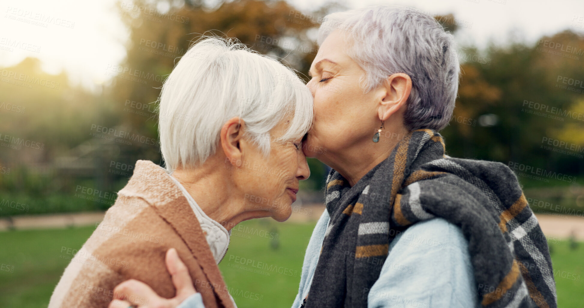 Buy stock photo Senior woman kissing her friend on the forehead for affection, romance and bonding on outdoor date. Nature, commitment and elderly female couple in retirement with intimate moment in garden or park.