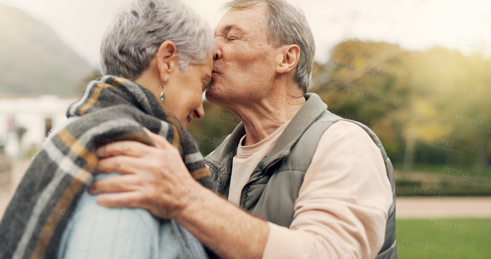 Buy stock photo Kiss, forehead and senior couple in a park with love, happy and conversation with romantic bonding. Kissing, old people and elderly man embrace woman with care, romance or soulmate connection outdoor