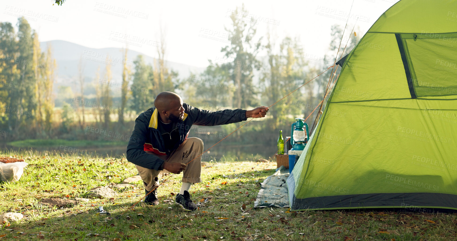 Buy stock photo Camping, tent and black man setup in nature for shelter on outdoor holiday, vacation and adventure, Campsite, traveling and male person with hammer for pins for gear in woods, forest and countryside