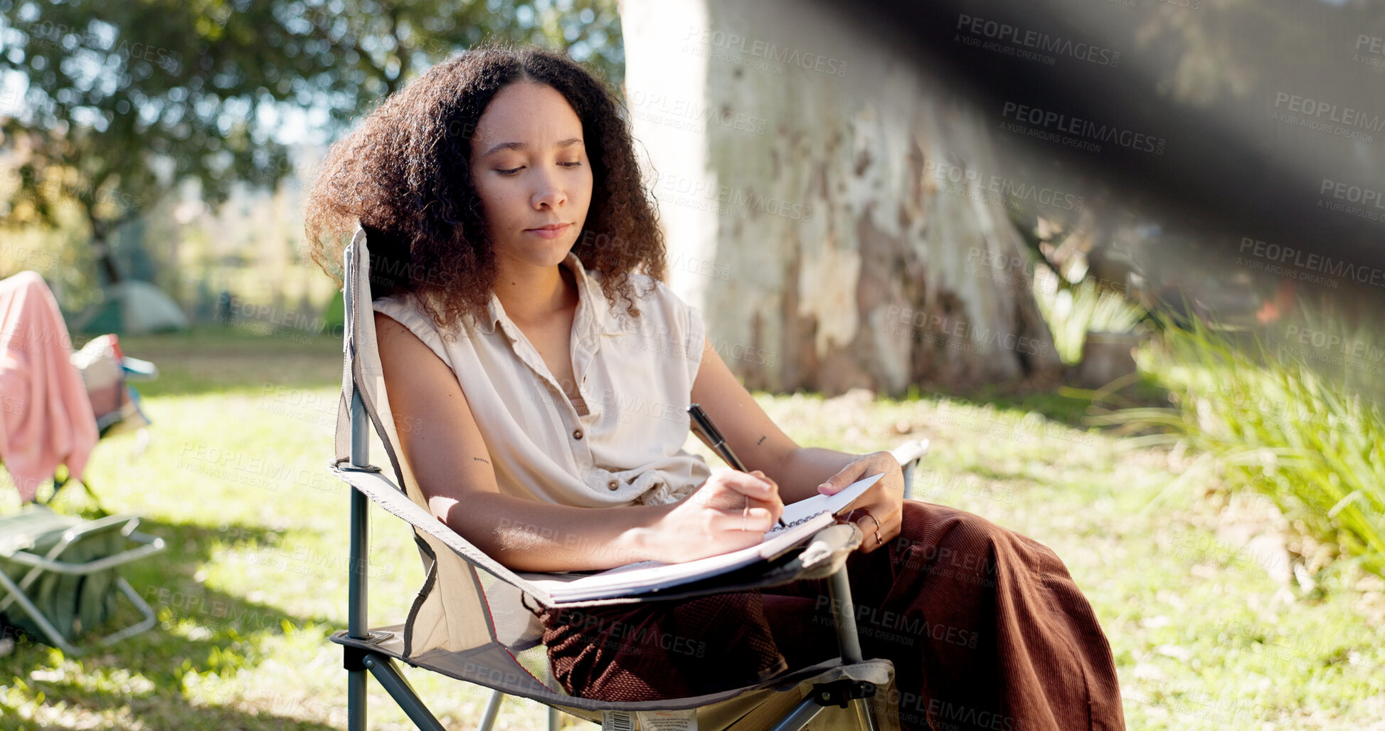 Buy stock photo Camping, morning and a woman writing in a book for travel notebook, journal or summer memory. Relax, reading and a girl or person in a chair while on a camp or document for holiday goals in nature