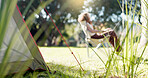 Nature, camp and woman sitting in a park, forest or the woods in the morning to relax with fresh air. Calm, peace and female person with chair in an outdoor green garden on weekend trip or adventure.