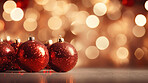 Shiny red christmas baubel decorations on table with bokeh copyspace