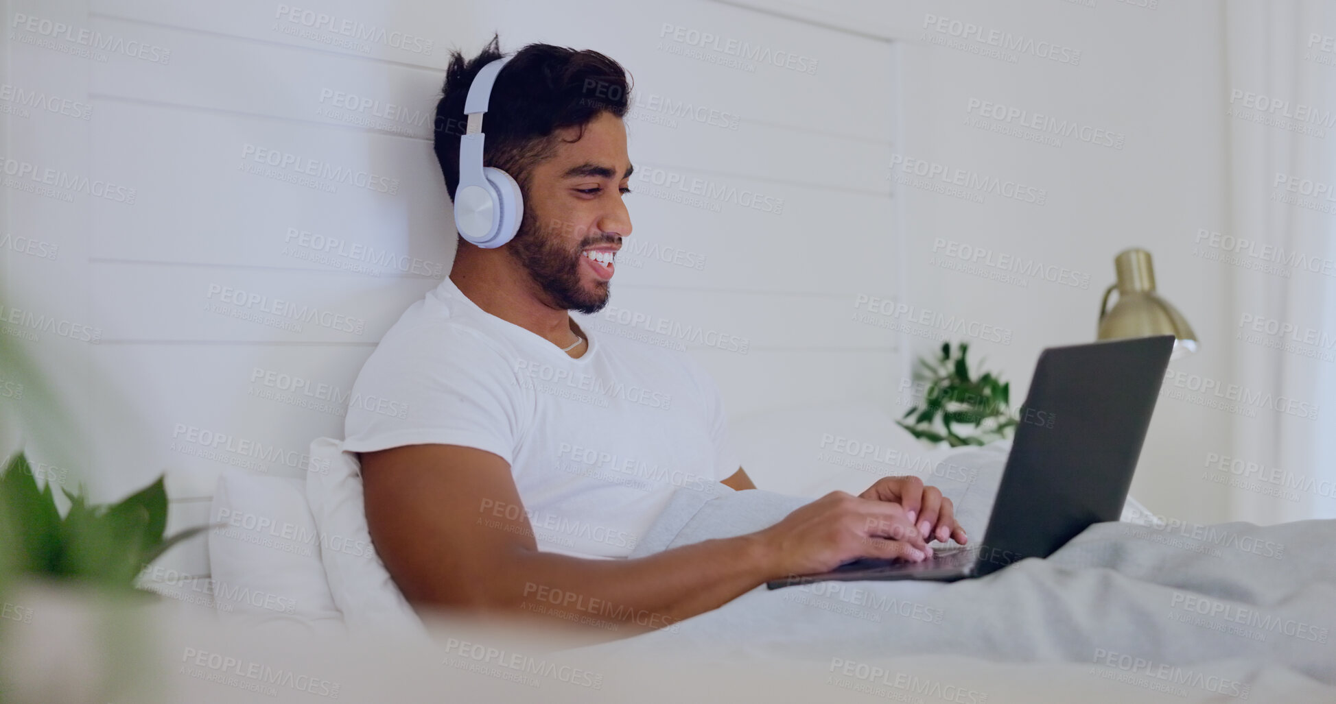 Buy stock photo Movie, laughing and man in bed with a laptop for streaming, meme or comedy show online. Funny, relax and guy in the bedroom watching a film, subscription service or video on computer with headphones