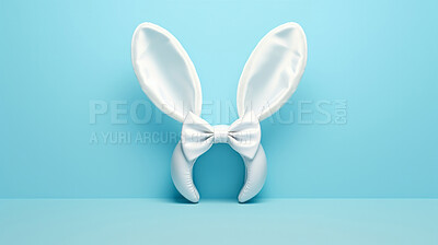 Buy stock photo White bunny ears and bow on blue copyspace background in studio. Festive Easter concept