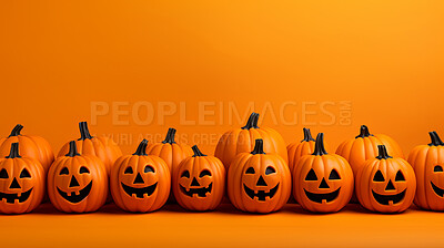 Row of carved halloween pumpkins on orange copyspace background.