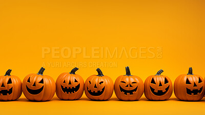 Row of carved halloween pumpkins on orange copyspace background.