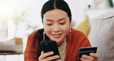 Asian woman, credit card and phone relaxing on her sofa online shopping, ecommerce and fintech easy payment. Young person in China typing bank information on cellphone for finance transaction at home