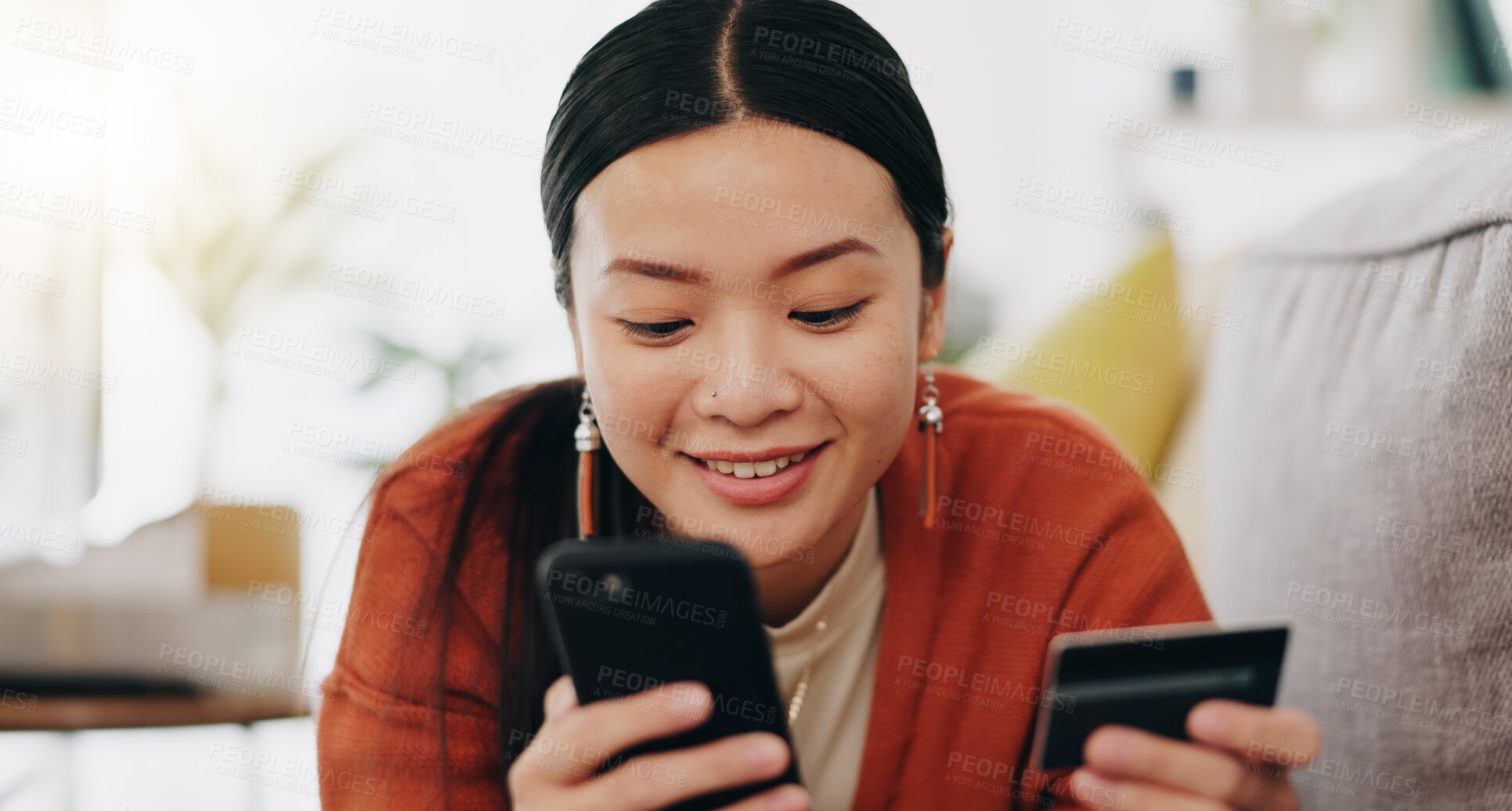 Buy stock photo Asian woman, credit card and phone relaxing on her sofa online shopping, ecommerce and fintech easy payment. Young person in China typing bank information on cellphone for finance transaction at home