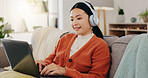Laptop, headphones and asian woman on couch with work from home opportunity in online or website copywriting. Remote worker or person in china typing on her computer and listening to music at home