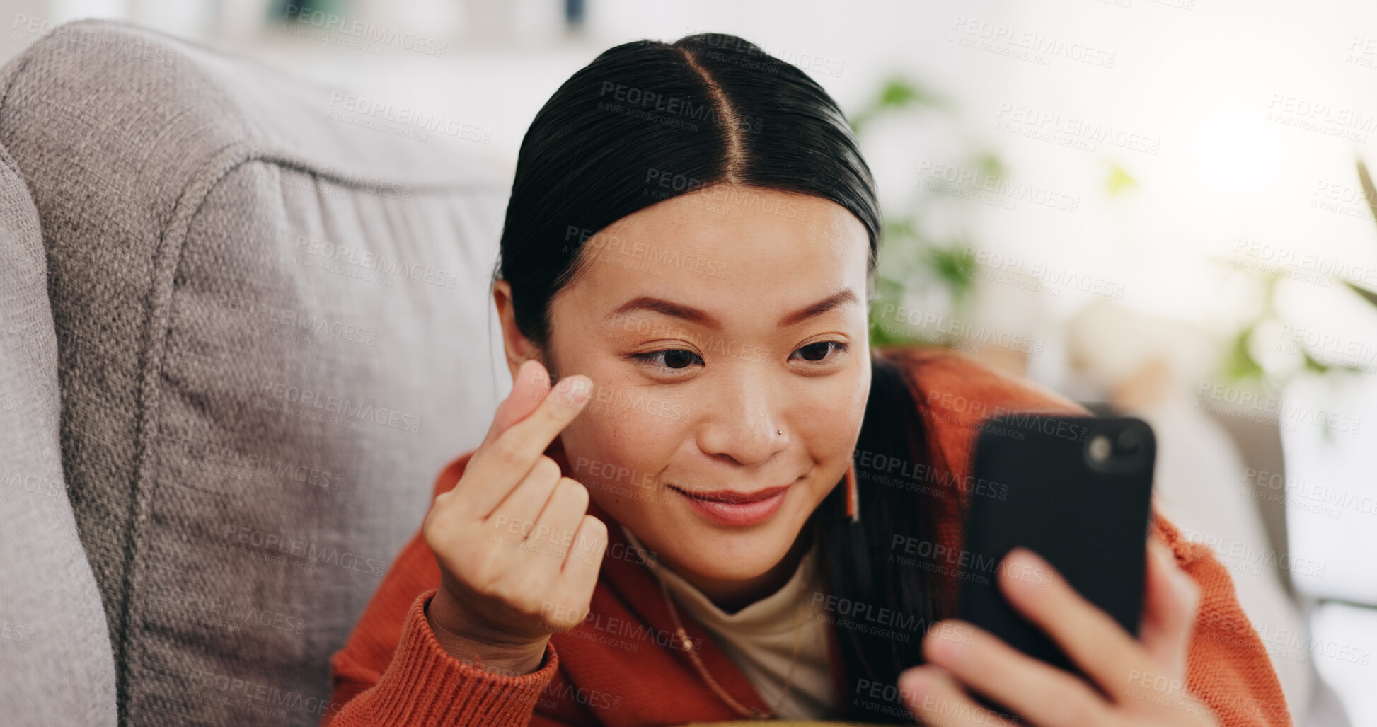 Buy stock photo Asian woman, selfie and lying on sofa with heart sign and love for profile picture, vlog or social media at home. Happy female relaxing with smile and hand signs for photo or online vlogging on couch