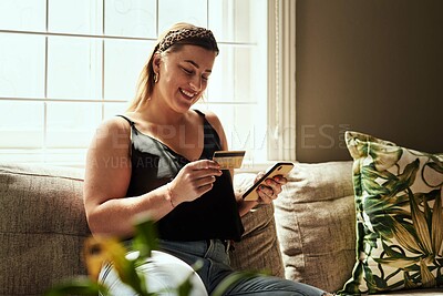 Buy stock photo Shot of a young woman using a smartphone and credit card on the sofa at home