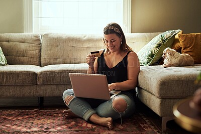 Buy stock photo Shot of a young woman using a laptop and credit card in her living room at home