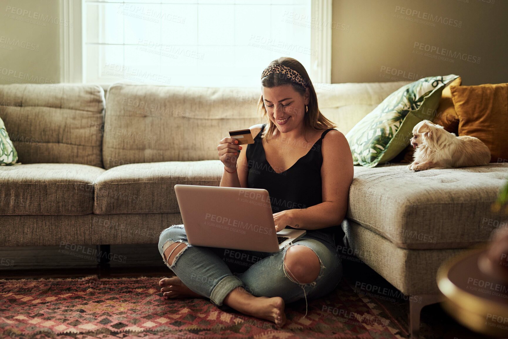 Buy stock photo Shot of a young woman using a laptop and credit card in her living room at home