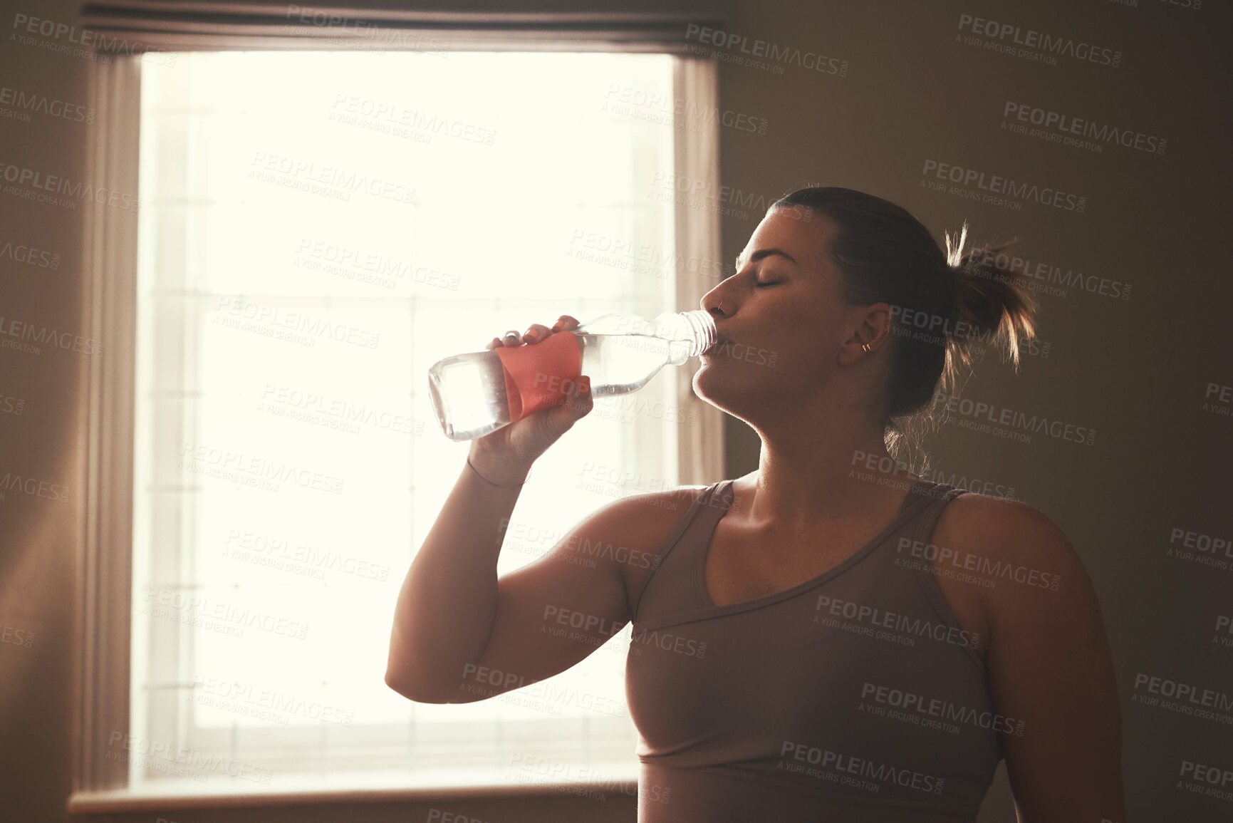 Buy stock photo Shot of a young woman drinking water after her workout at home