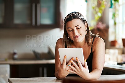 Buy stock photo Shot of a young woman using a digital tablet in the kitchen at home