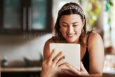 Buy stock photo Shot of a young woman using a digital tablet in the kitchen at home
