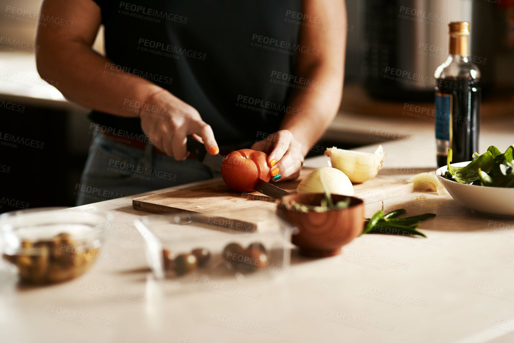 Buy stock photo Cropped shot of a woman slicing a tomato while preparing a meal at home