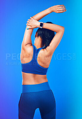 Buy stock photo Rearview shot of a young sportswoman stretching her arms against a blue background