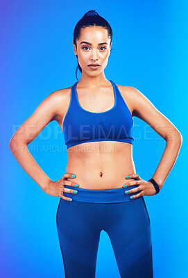 Buy stock photo Studio portrait of an attractive young sportswoman posing with her hands on her hips against a blue background