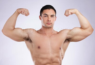 Buy stock photo Shot of a young male athlete flexing his biceps against a grey studio background