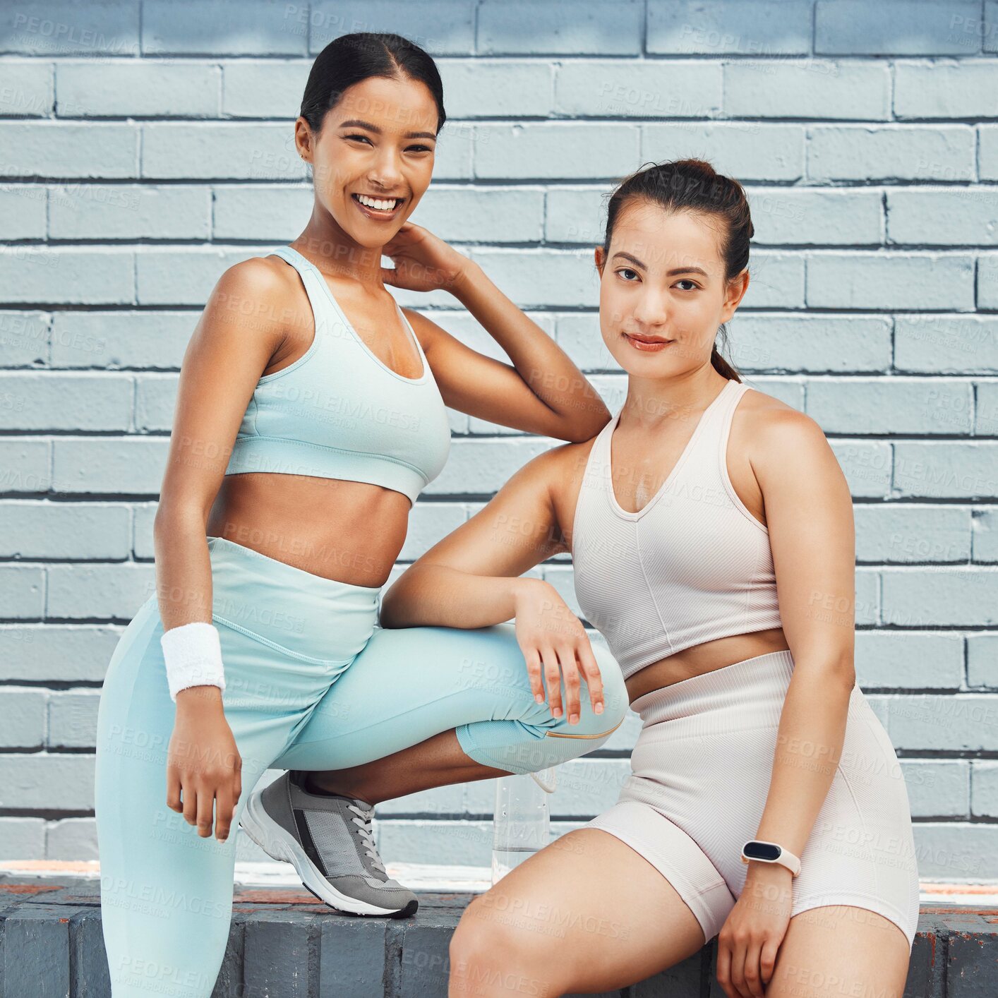 Buy stock photo Fitness, exercise and friends with a sports woman team in the city for a workout on a brick wall background. Teamwork, training and health with a female athlete and friend resting after a routine