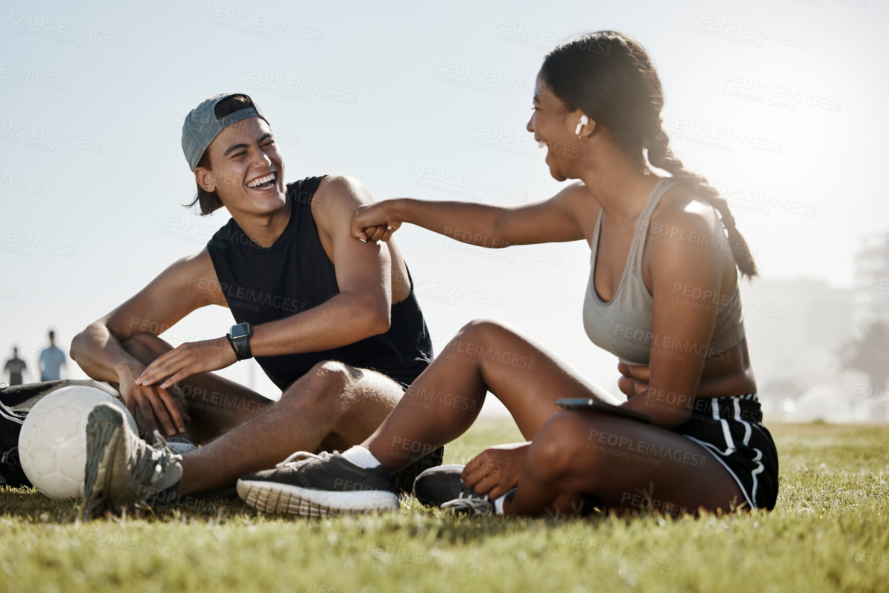 Buy stock photo Fitness, friends and soccer grass break by man and woman relax, laugh and enjoy conversation on a soccer field. Wellness, couple and cheerful interracial lady and guy bonding after football training