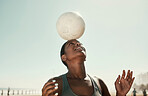 Head balance, sports and soccer ball with a black woman athlete in the sun and nature. Fitness, balancing concentration and exercise of a person busy with workout, training and healthy cardio