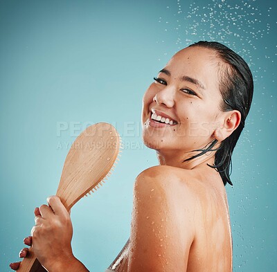 Buy stock photo Beauty, brush and shower by woman in studio for cleaning, hair care and wellness on blue background mockup. Portrait, water splash and asian girl model happy, relax and skincare, hair and face care 