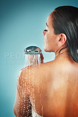 Beauty, skincare and woman in a shower for grooming, hygiene and hair against a blue background. Water, cleaning and girl in water splash for wellness, routine and skin, self love and studio pamper