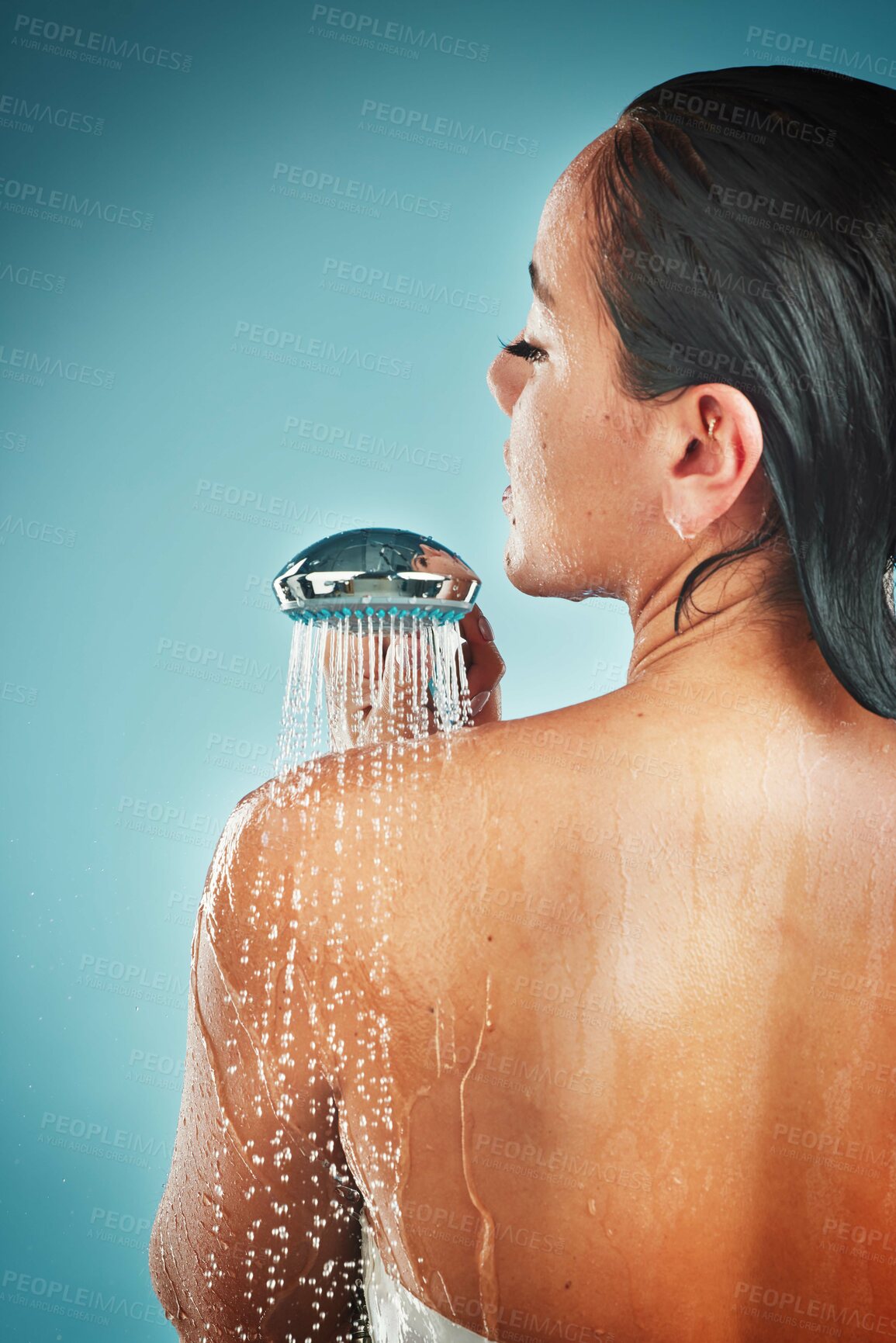 Buy stock photo Beauty, skincare and woman in a shower for grooming, hygiene and hair against a blue background. Water, cleaning and girl in water splash for wellness, routine and skin, self love and studio pamper