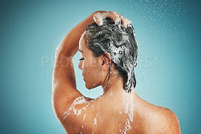 Beauty, shower and woman cleaning, haircare and shampoo while washing against a blue studio mock up background. Back, model and clean in bathroom for skincare, health and wellness with water and soap