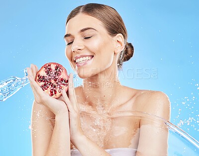 Buy stock photo Beauty, water and pomegranate with a model woman in studio on a blue background for nutrition or hydration. Food, cleaning and skincare with an attractive young female posing to promote health