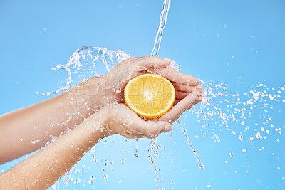 Buy stock photo Water splash, zoom or orange in hands for skincare wellness, nutrition or health in blue background studio. Water, shower or cleaning fruit in hand for natural, organic or fresh food vitamin C splash