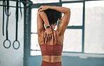 Fitness, back view or black woman in gym stretching to warm up body or relax arm muscles in workout exercise. Wellness, flexible or healthy sports girl training or exercising with focus or motivation
