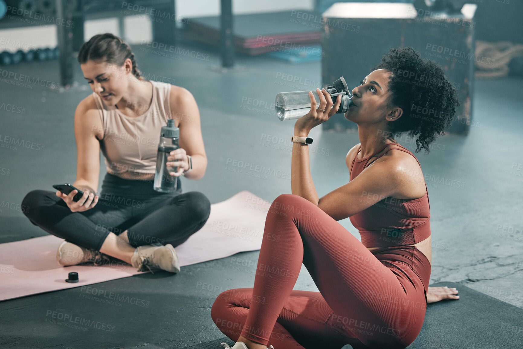 Buy stock photo Fitness, relax and drinking water with women in gym for workout, exercise and cardio. Training, wellness and sweating with friends resting on floor of sports center for health, fatigue and tired