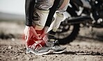 Ankle, injury and motorcycle with the hands of a man holding his joint in pain while outdoor for a race. Sports, training or anatomy with a male athlete suffering an accident on a ride for recreation