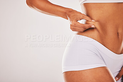 Buy stock photo Fat, weight and woman touching her stomach isolated on a grey studio background with mockup space. Skin, cellulite and hands of a model feeling her body for insecurity, health and tummy tuck