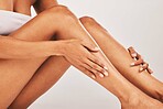 Woman, hands and legs in skincare beauty, cosmetics or moisturizer against gray studio background. Hand of female touching soft, smooth or gentle leg for healthy skin, wellness or self love and care