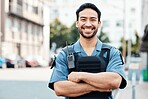 Portrait, happy or policeman in city with arms crossed for law enforcement, security or street safety. Confident cop, smile or proud Asian security guard on patrol in urban town for crime or justice