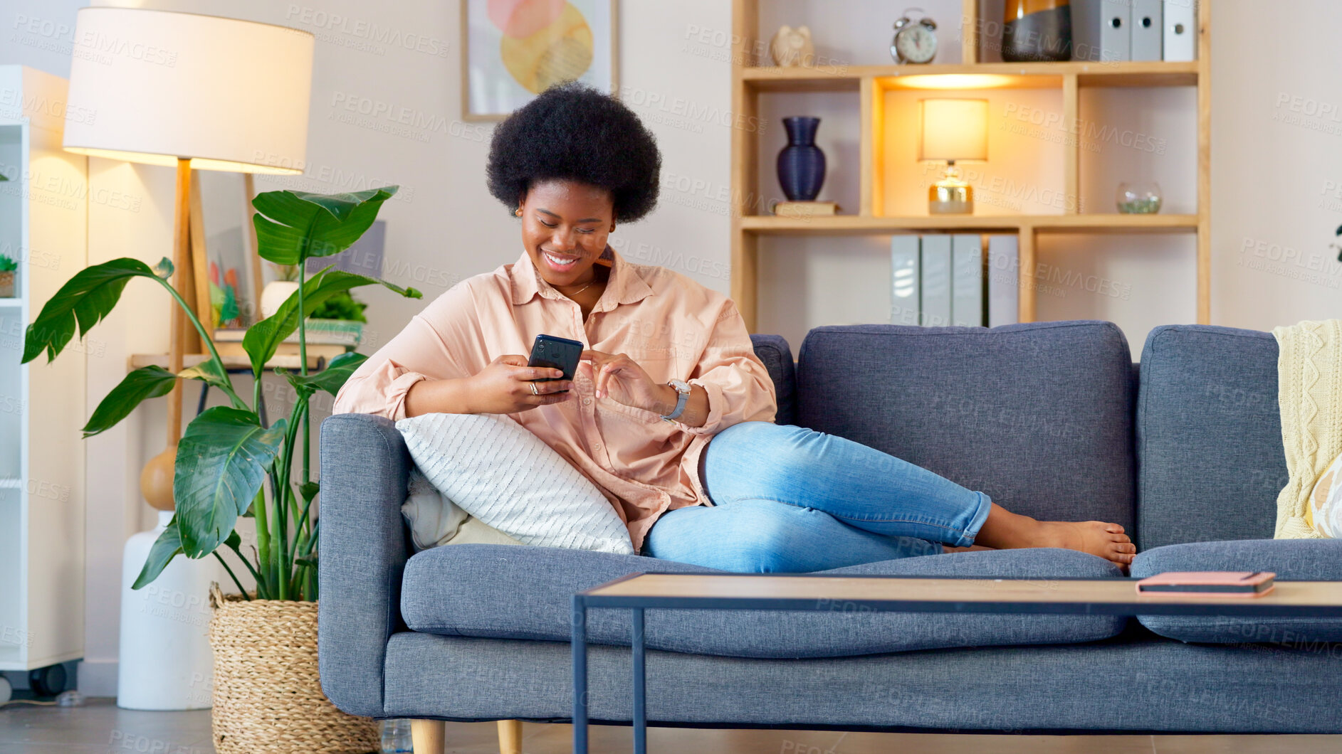 Buy stock photo Black woman, phone and relax on living room sofa with text and funny web meme at home. Happy, African female person smile and browsing social media on mobile app on the couch with website scroll