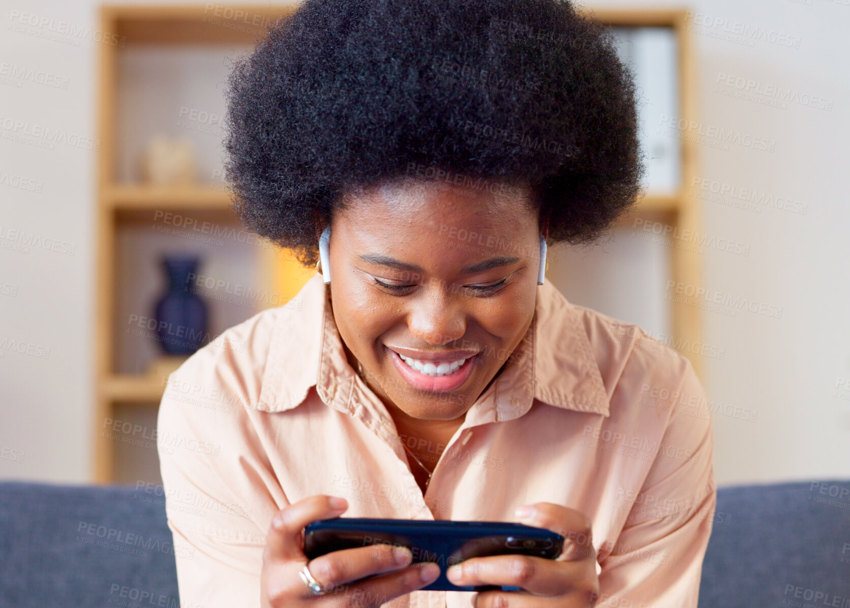 Buy stock photo Face, phone and gaming with a black woman on a sofa in the living room of her home closeup for entertainment. Smile, mobile app and a happy young gamer girl playing an online video game in the house