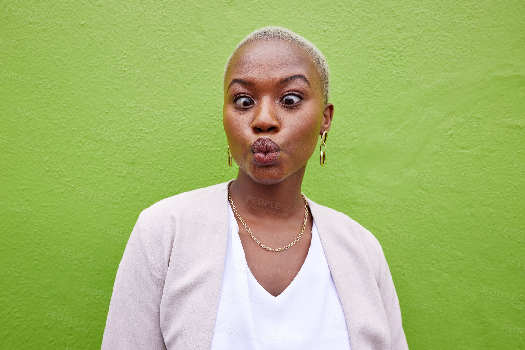 Buy stock photo Happy, silly and young black woman by a green wall with trendy, classy and elegant jewelry and outfit. Happiness, goofy and African female model with positive and confident attitude with fashion.