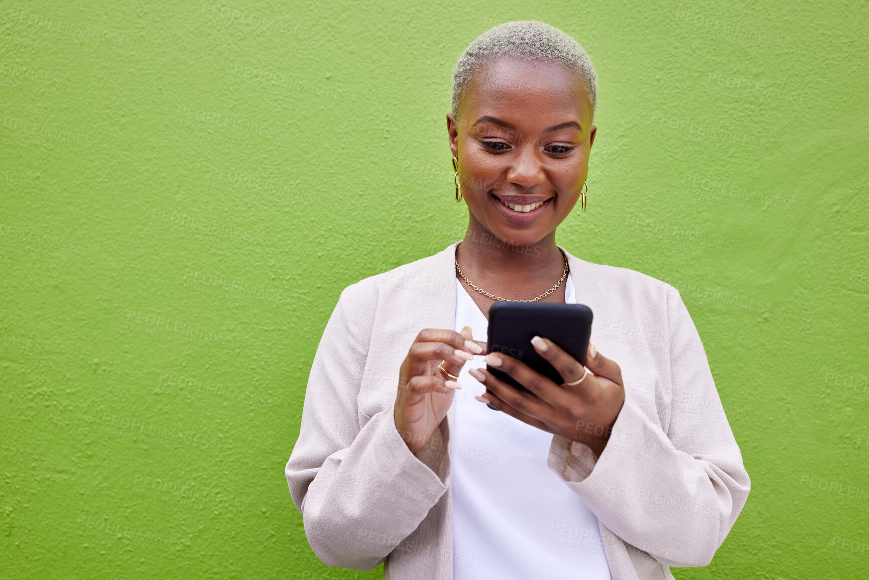 Buy stock photo Black woman, smile and phone for communication by a wall or green background with internet. African female person outdoor with a smartphone for social media, networking and mobile app chat space