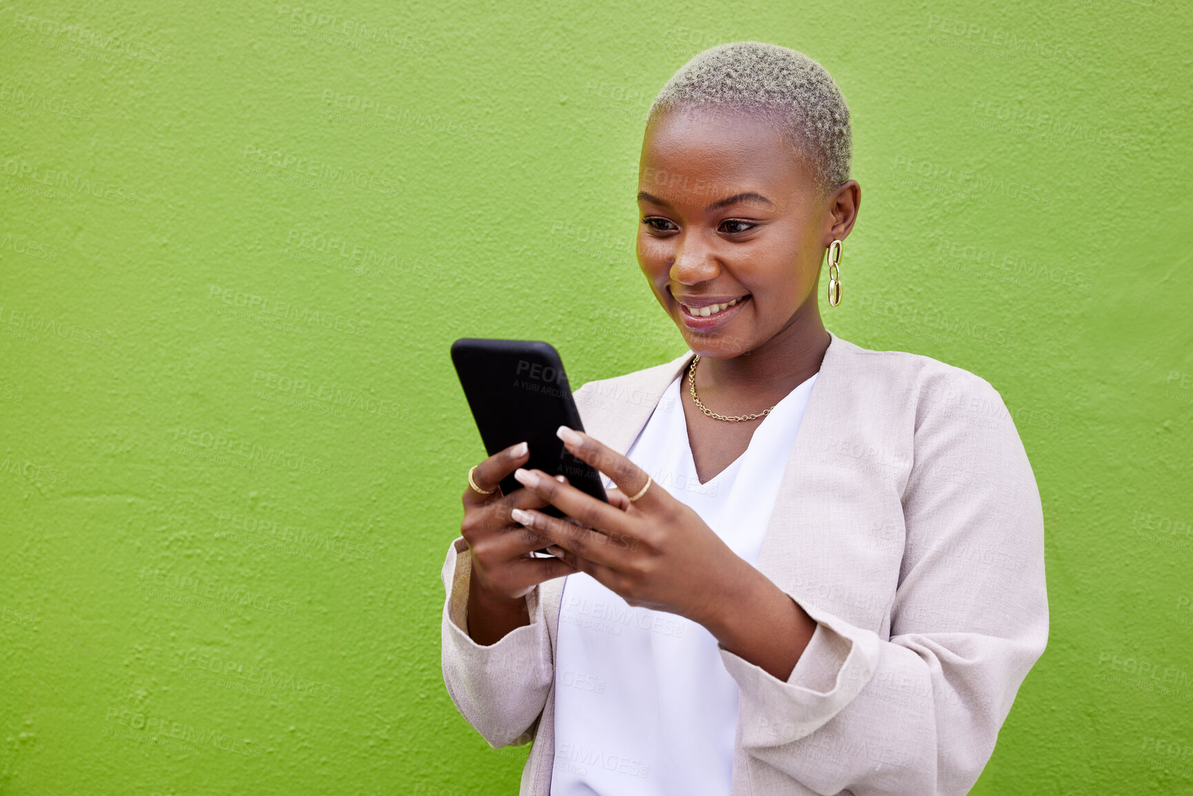 Buy stock photo Black woman, typing and phone for communication by a wall or green background with internet. African person with a smartphone reading social media message, networking and mobile app chat space